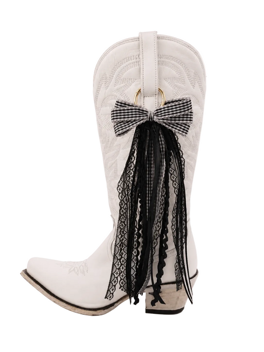 A white boot featuring a clip on black boot bow 
